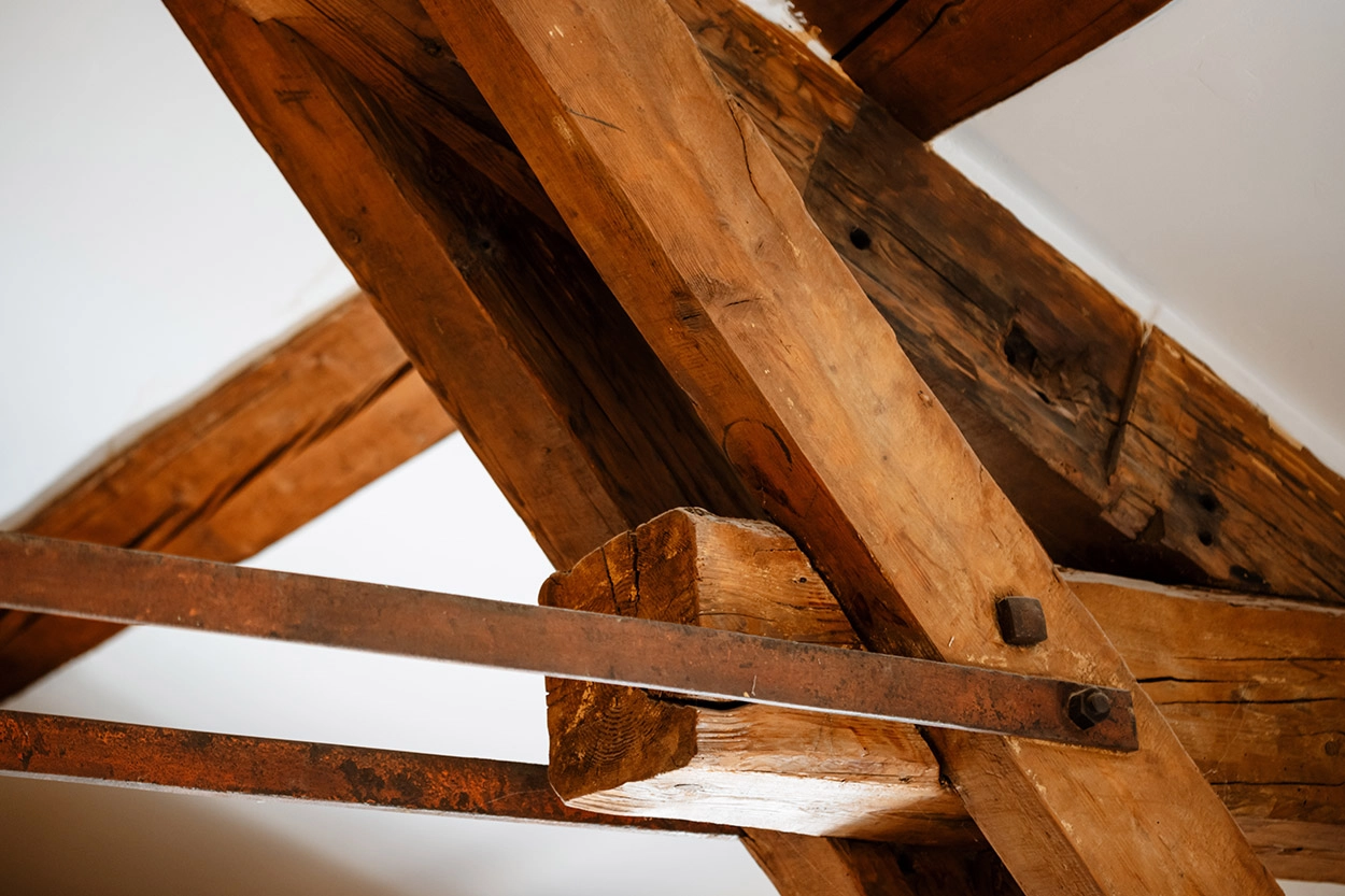 Charpente traditionnelle en bois avec assemblages renforcés par des tirants métalliques – Gros Lilian à Montréal et Condon